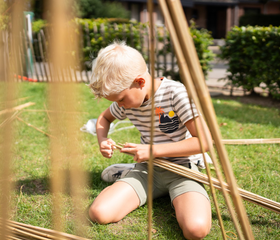 Kind bouwt met bamboestokken tijdens een activiteit van het animatieteam op Resort Veluwe.