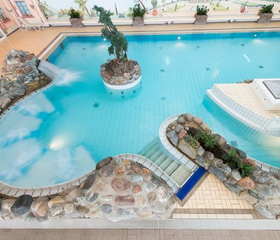 Het tropische binnenbad van zwemparadijs Rother Lagune in Rhön Park Aktiv Resort, met rotsformaties en een standbeeld van een zeepaard.