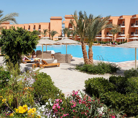 Het zwembad van Three Corners Sunny Beach Resort in Egypte, omgeven door een prachtig aangelegde tuin met palmbomen en bloemen.