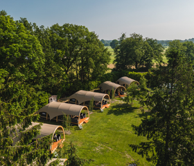 Een luchtfoto die een rij luxe lodges laat zien, prachtig verscholen in het groene en bosrijke landschap van het vakantiepark in Overijssel.