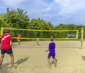 Mensen spelen volleybal op het beachvolleybalveld van de camping