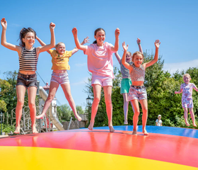 Kinderen springen samen op de grote vrolijk gekleurde air trampoline van de camping