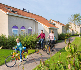 Een gezin fietst vrolijk tussen de vakantiehuizen op Vakantiepark De Soeten Haert in Renesse.