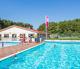 Kinderen en ouders genieten van het zonnige, verwarmde buitenzwembad op Roompot Vakantiepark Egmond aan Zee.
