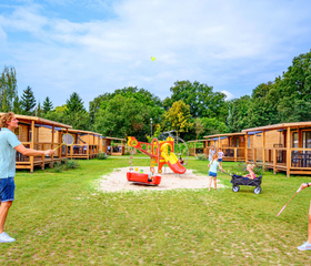 Moderne chalets en lodges gelegen aan een groen speelveld op de camping in Gelderland