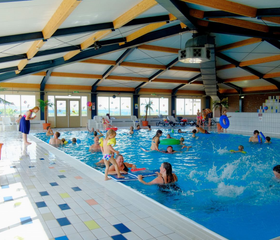 Het overdekte binnenzwembad van Ferienresort Cochem vol met spetterende en zwemmende kinderen en hun families.