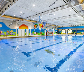 Het ruime binnenzwembad van Vakantiepark Hunzedal, met vrolijke wanddecoraties en ruimte om te zwemmen en te spelen voor het hele gezin.