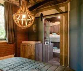 Het sfeervolle, houten interieur van de boomhut op Vakantiepark Molke, met een doorkijkje naar de knusse bedstee voor de kinderen.