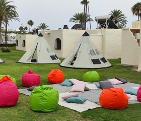 De gezellige chill-out zone voor kinderen bij Parque Cristobal met tipi tenten en vrolijk gekleurde zitzakken op het gras.