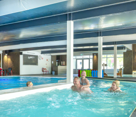 Gezin zwemt samen in het overdekte zwembad van de camping