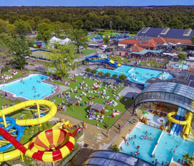 Luchtfoto van het enorme waterpark op Capfun Camping Wondermolen met meerdere zwembaden en spectaculaire glijbanen.