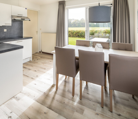 De open keuken met moderne eethoek in een vakantiehuis op Vakantiepark Zeeland Village, met uitzicht naar buiten.