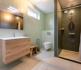 Nette en moderne badkamer in een waterwoning in Terherne, voorzien van een ruime inloopdouche met regendouchekop.