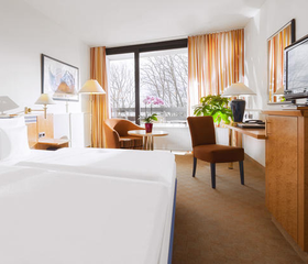 Een lichte en ruime familiekamer in Dorint Hotel Arnsberg, met een comfortabel bed en uitzicht op de winterse natuur.
