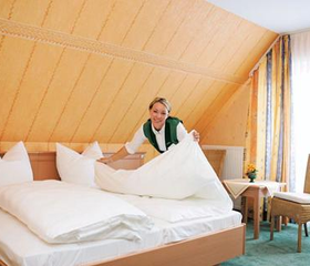 Een medewerker van Göbels Landhotel maakt een heerlijk fris bed op in een van de comfortabele hotelkamers.