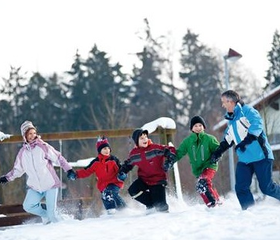 Een vrolijke familie rent hand in hand door de diepe sneeuw tijdens hun wintervakantie bij Landal Salztal Paradies in de Harz.