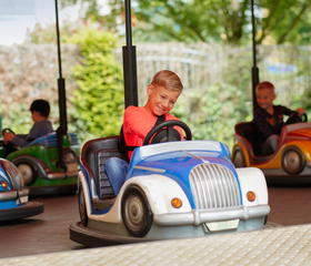 Jonge jongen heeft plezier in een blauw-witte botsauto in het attractiepark van Wunderland Kalkar.