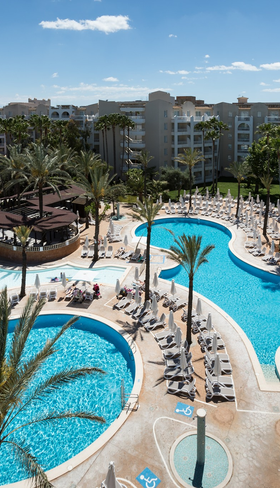 Een overzichtsfoto van het grote zwembadcomplex van Aparthotel Protur Safari Park op Mallorca, met lagune-stijl baden en palmbomen.