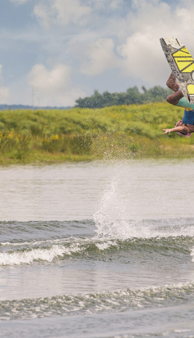 Persoon aan het wakeboarden op de Nederrijn bij Vakantiepark Bad Nederrijn, een perfecte locatie voor watersport met het gezin in Gelderland.