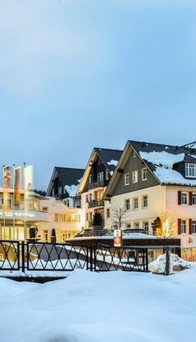 De sfeervol verlichte buitenkant van het Best Western hotel en appartementen in Willingen, bedekt met een dik pak sneeuw in de avond.