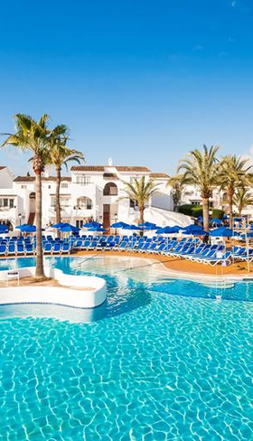 Het grote, helderblauwe hoofdzwembad van Bouganvilla Hotel & Appartementen op Mallorca, omringd door witte gebouwen en palmbomen.