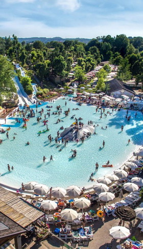 Overzicht van het grote lagune zwembadcomplex op Camping Altomincio Family Park aan het Gardameer, vol met zwemmende gezinnen en omringd door ligbedden en bomen.