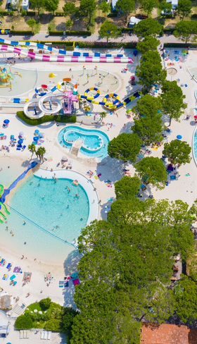 Luchtfoto van het immense Aquapark Laguna op Camping Union Lido, met diverse lagune zwembaden, witte zandstranden en veel vakantiegangers.