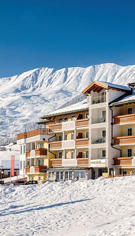 Hotel in de sneeuw met een hoge besneeuwde bergtop achter zich
