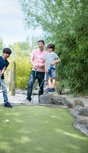 Een gezin met twee zonen speelt een potje midgetgolf op de avontuurlijke golfbaan van Center Parcs Port Zélande in Zuid-Holland.