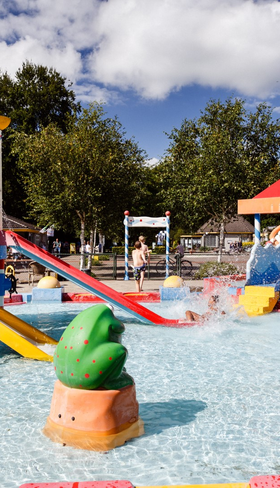De kleurrijke waterspeeltuin (spraypark) van RCN de Roggeberg in Friesland, vol met glijbanen, sproeiers en speeltoestellen voor kinderen.