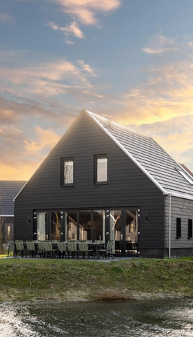 Een luxe, moderne, zwarte vakantiewoning aan het water op Dormio Resort Nieuwvliet-Bad in Zeeland, tijdens een kleurrijke zonsondergang.