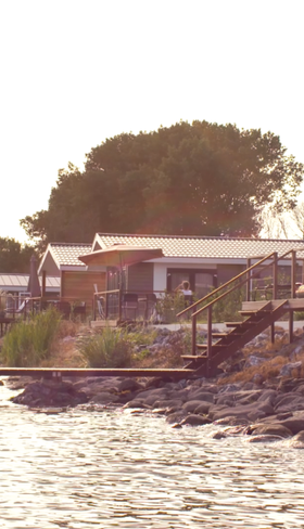 Vakantiehuizen aan de waterkant van EuroParcs Markermeer in Noord-Holland, met de zon die over het water schijnt.