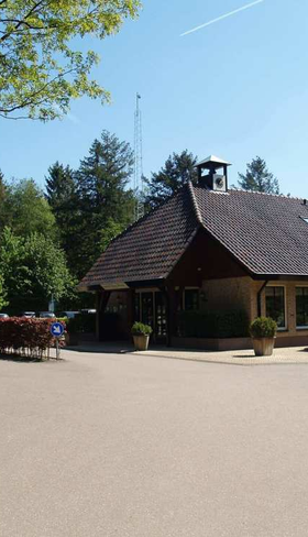 Het restaurant met een ruim en zonnig terras op EuroParcs Resort De Utrechtse Heuvelrug, omringd door groene bomen.