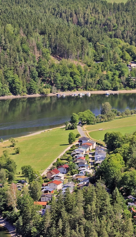 Luchtfoto van Hohenwarter Seehof in Nedersaksen, met het vakantiepark aan het meer, omringd door groene bossen, ideaal voor gezinsvakanties.