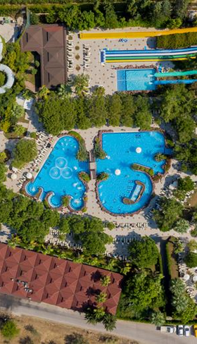 Luchtfoto van het enorme aquapark van Hotel Ali Bey Club in Side, Turkije, met talloze zwembaden en spectaculaire waterglijbanen.