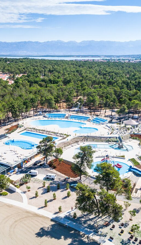 Luchtfoto van het uitgestrekte zwembadcomplex van Zaton Holiday Resort in Kroatië, omgeven door groene pijnbomen, een topkeuze voor een kindvriendelijke vakantie.
