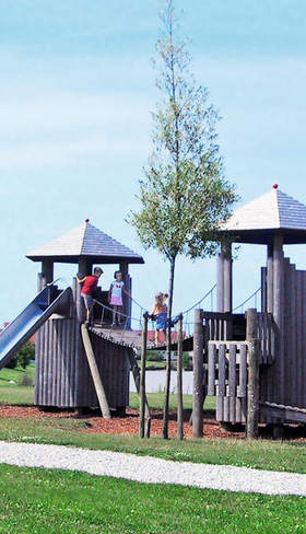 Kinderen spelen in de houten buitenspeeltuin met glijbaan en klimtorens op Vakantiepark Sandur in Emmen.