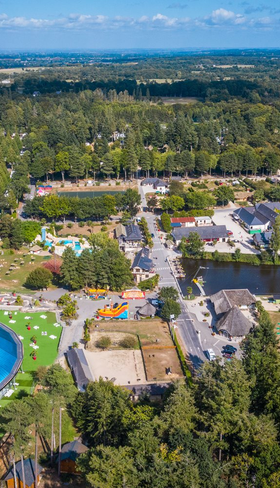 Luchtfoto van het uitgestrekte vakantiepark Domaine des Ormes in Bretagne, Frankrijk, met het grote overdekte waterpark, diverse zwembaden, het kasteel en de groene omgeving.