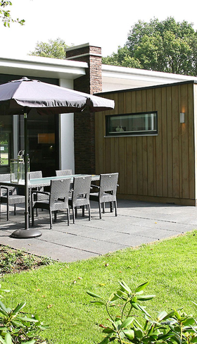 Een moderne, duurzame bungalow met houten gevel en een ruim terras met tuinmeubilair op Landal Amerongse Berg.