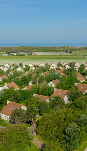 Luchtfoto van Landal Beach Resort Ooghdyne, met de vakantiehuizen tussen het groen en de Noordzeekust op de achtergrond.