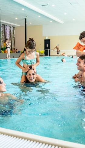 Gezin met kinderen speelt en lacht in het overdekte binnenzwembad van Landal de Vers in Noord-Brabant.
