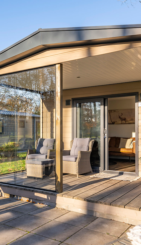 De luxe, overdekte houten veranda van een moderne lodge op Landal De Vlinderhoeve, met een comfortabele tuinset.