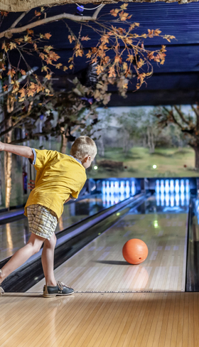 Een jongen en een meisje zijn aan het bowlen op de sfeervolle bowlingbaan in het indoorspeelparadijs van Landal Heideheuvel.
