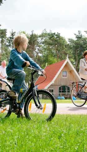 Een gezin met kinderen fietst over een pad op het bosrijke en autoluwe vakantiepark Landal Hellendoornse Berg.