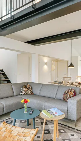 Ruime en moderne woonkamer met grote bank, eettafel en open keuken in een vakantiewoning op Landal Marissa, ideaal voor gezinnen.