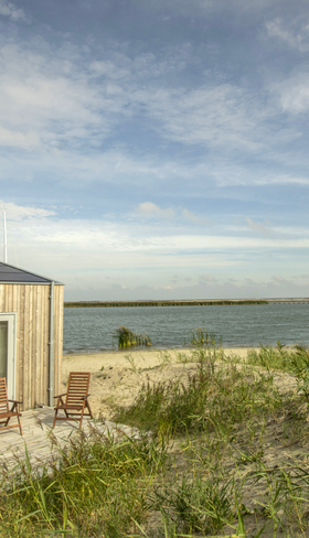 Een duurzaam, houten eilandhuisje van Landal Marker Wadden, gelegen op het strand met uitzicht over het water van het Markermeer.