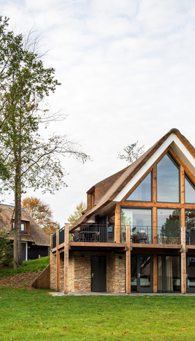 Een luxe houten vakantievilla met grote ramen op Landal Puur Exloo in Drenthe, prachtig gelegen in het groene landschap van de Hondsrug.