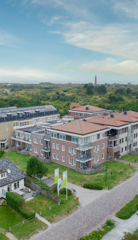 Luchtfoto van de moderne appartementencomplexen van Landal Vitamaris, omgeven door het groene landschap van Schiermonnikoog.