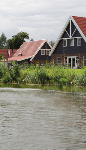 Karakteristieke vakantiehuizen met rode daken, direct gelegen aan het kabbelende water van Landal Waterparc Veluwemeer in Flevoland.