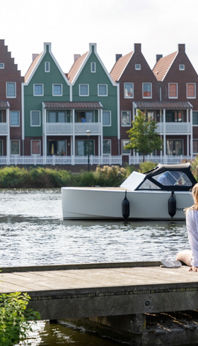 Een moeder en dochter genieten van het uitzicht over het water, zittend op een steiger met de typische Volendamse vakantiehuizen op de achtergrond.